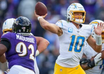 Justin Herbert lanzando un pase ante la defensa de Ravens.