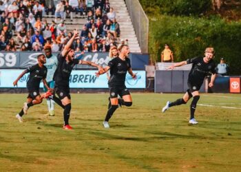 Charlie Dennis festejando su gol con sus compañeros ante el Loyal.