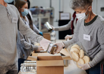 Grupo de voluntarios que trabajan en el centro de donación de caridad comunitaria, banco de alimentos y concepto de coronavirus.
