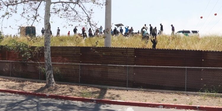 Migrantes en muro fronterizo lado estadounidense