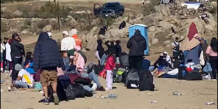Decenas de migrantes improvisan un campamento junto al muro fronterizo en el Ejido Jacumé